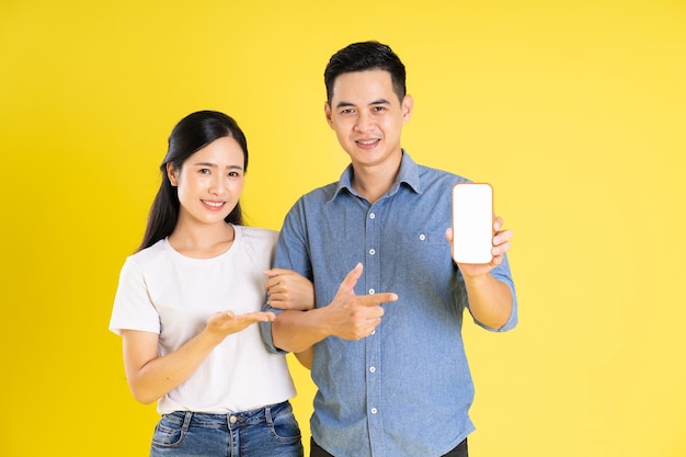 Image of asian couple posing on yellow background