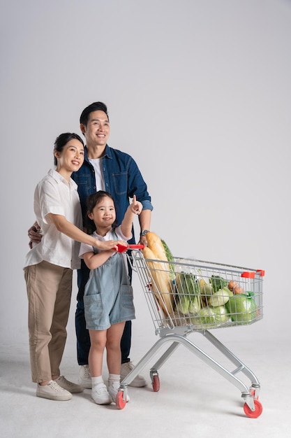 Image of Asian family pushing a supermarket cart while shopping isolated on white backgroundxA