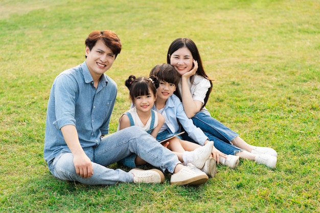 Image of an asian family sitting together on the grass at the park