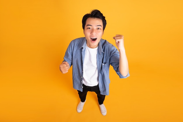 Image of asian man posing on a yellow background