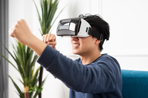 Image of asian man wearing virtual reality glasses on purple background