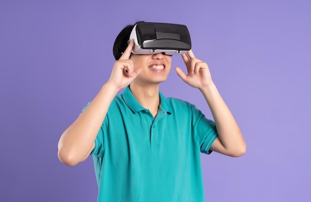 Image of asian man wearing virtual reality glasses on purple background