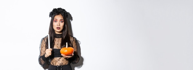 Image of asian woman panicking being scared of witchcraft on halloween standing in witch costume wit