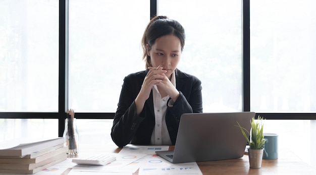 Image of an Asian woman who is tired and overthinking from working with a tablet at the office