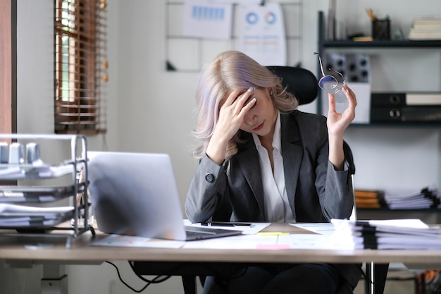 Image of an Asian woman who is tired and overthinking from working with a tablet at the office