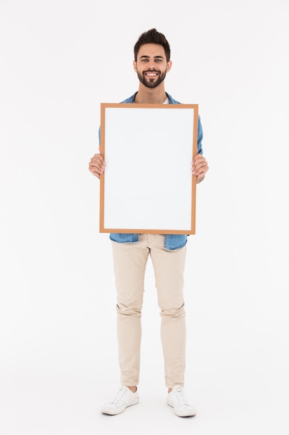 Photo image of attractive bearded man holding empty placard in frame and smiling isolated over white wall