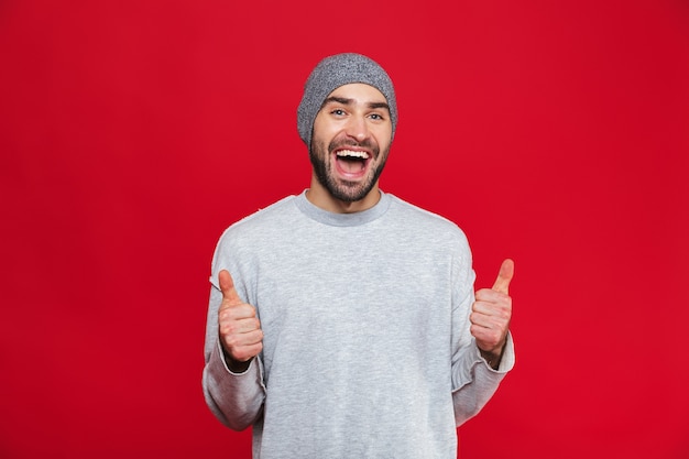 Image of attractive man 30s having stubble laughing and showing thumbs up