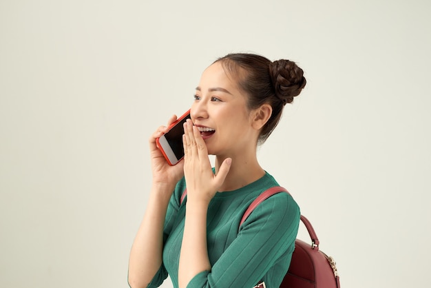 Image of a beautiful happy girl posing isolated over white background talking by mobile phone.