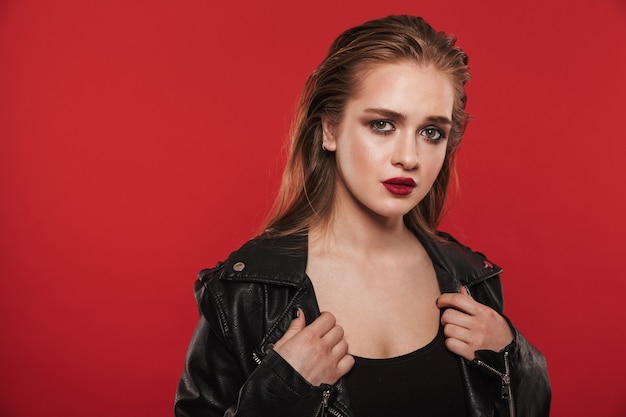 Image of a beautiful young amazing woman with bright makeup red lipstick posing over red wall.