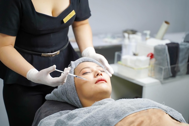 Image of beauty doctor in medical grove holding beauty skin syringe injecting the customer's face Beauty skin concept