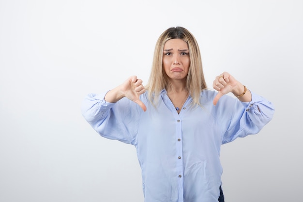 Image of blonde woman looking at camera on white wall.