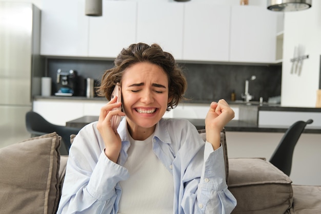 Image of brunette girl receive great news over the phone got the job celebrates talks on mobile phon