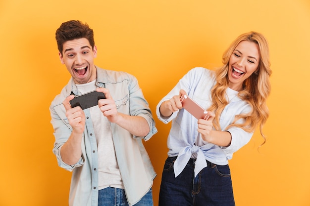 Image of cheerful man and woman playing together video games on mobile phones