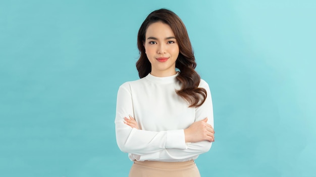 Image of cheerful woman in basic tshirt smiling at camera while standing with arms crossed isolated over blue background