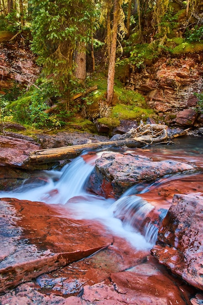 Image of Close up of small waterfalls over red rocks with mossy cliffs