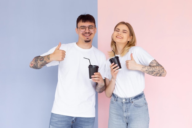 Image of content couple man and woman in denim clothes smiling while holding takeaway coffee cups