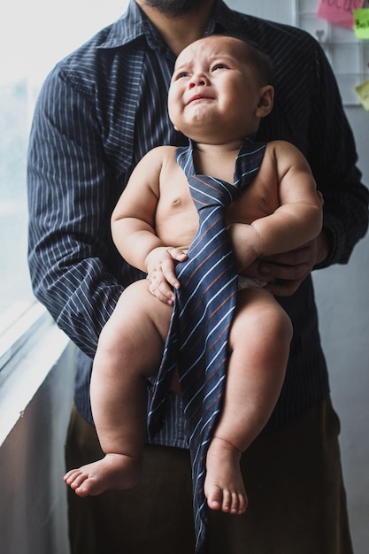 Image of cute little baby wearing a tie in young dad's hands Newborn photo cute little kids concep