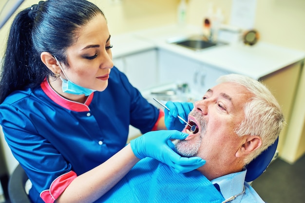 Image of dentist using angled mirror while examining patient's teeth