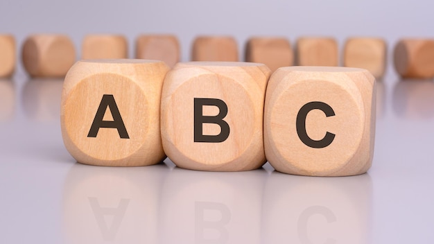 the image depicts three wooden blocks with the letters ABC in focus reflecting on the table