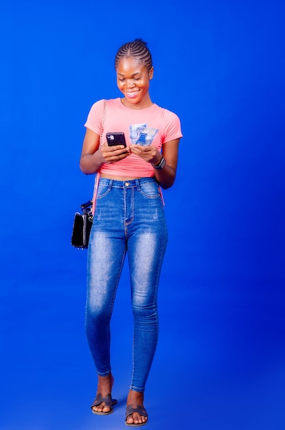 Image of excited young lady isolated over blue backgroundmobile phone holding money