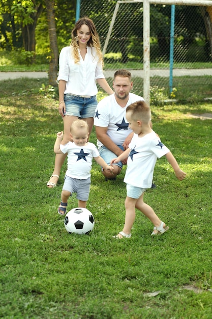 Image of family motherfather and sons playing ball in the park