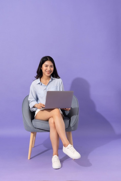 Image of girl sitting on sofa isolated on purple background