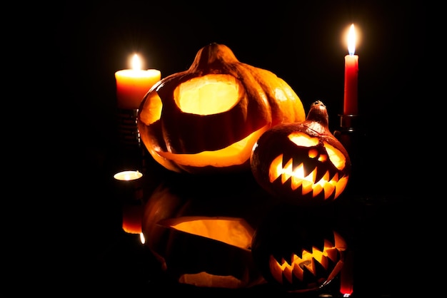 Image of halloween pumpkins with burning mouths candles on empty black background