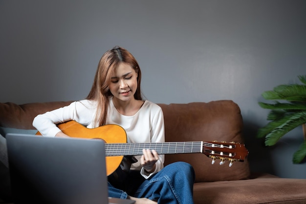 Image of happy beautiful woman playing guitar and composing song