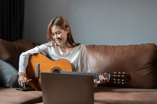 Image of happy beautiful woman playing guitar and composing song