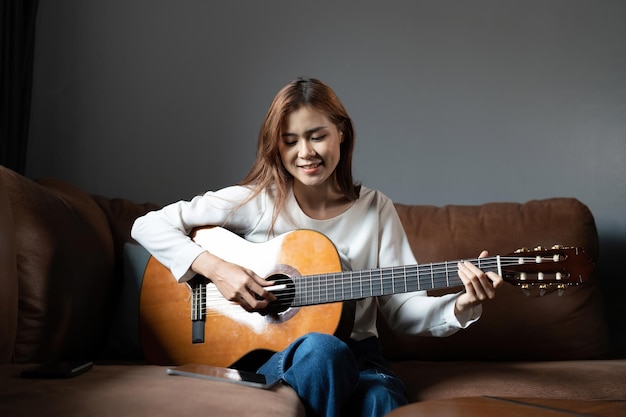 Image of happy beautiful woman playing guitar and composing song