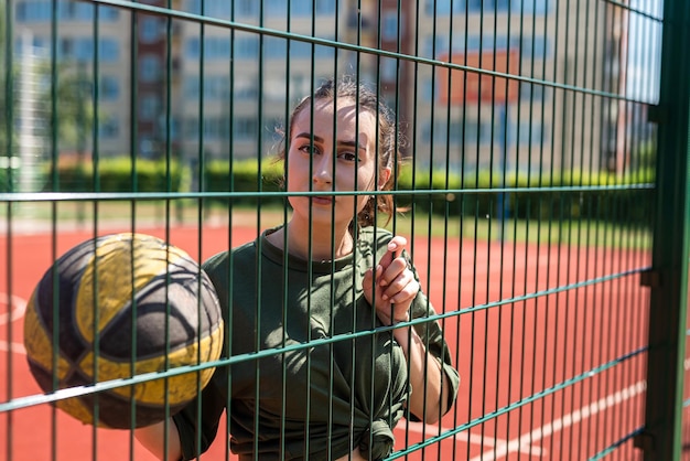 An image of a happy woman about to throw a ball into a basket