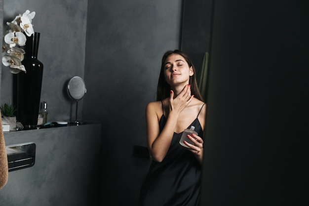 Image of a happy young beautiful woman in bathroom take care of her skin.