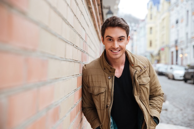 Image of happy young man walking on the street and looking at camera.