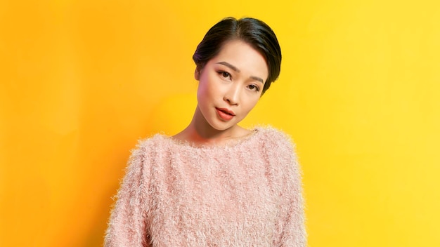 Image of happy young woman standing isolated over yellow background Looking camera