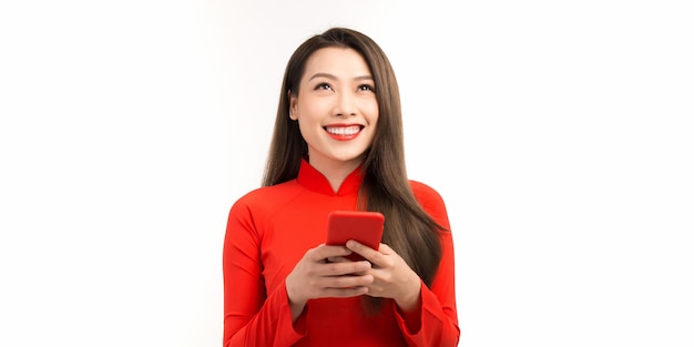 Image of happy young woman in vietnamese traditional dress chatting by phone standing isolated over white Looking aside