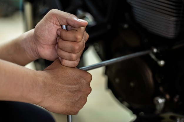 Image is Close up, Auto mecanic are repairing a motorcycle Use a wrench and a screwdriver to work.