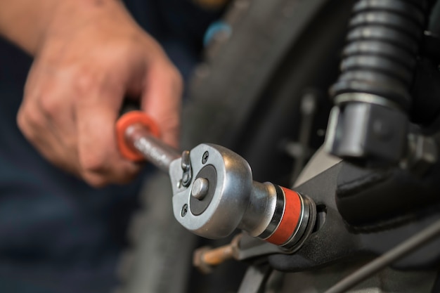 Image is Close up,People are repairing a motorcycle Use a wrench and a screwdriver to work.