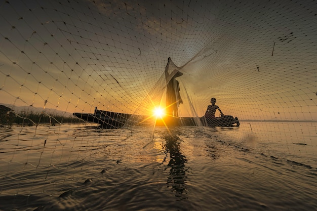 Image is silhouette. Fishermen Casting are going out to fish early in the morning with wooden boats, old lanterns and nets. Concept Fisherman's life style.