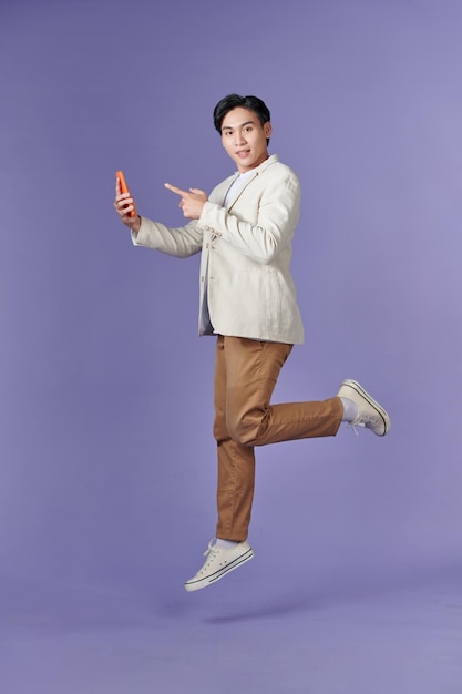 Image of jumping up asian man holding smartphone in hand