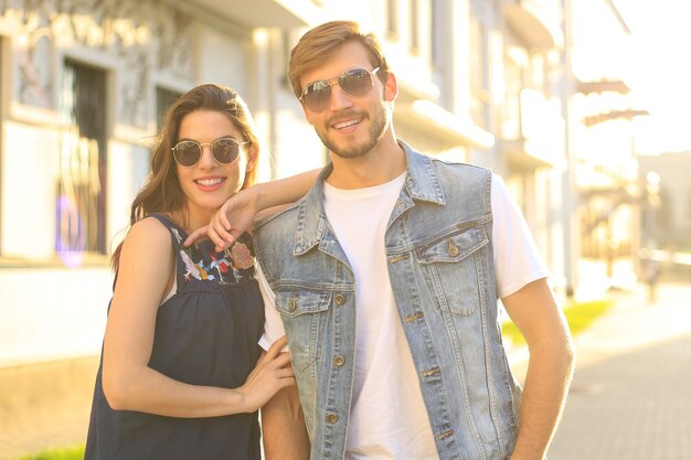 Image of lovely happy couple in summer clothes smiling and holding hands together while walking through city street.