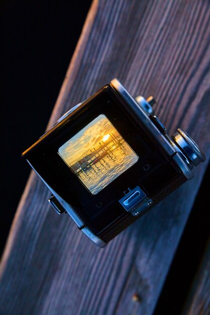 Image of Old camera with viewing point revealing a golden sunrise with water and a dock