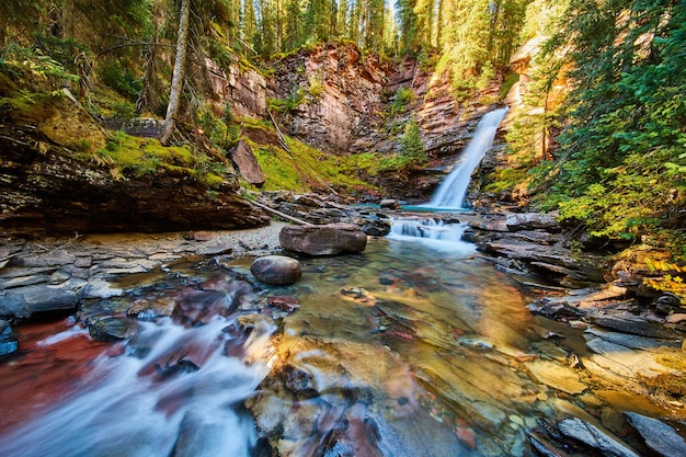 Image of Peaceful and tranquil waterfall leading to shallow river in canyon with mossy rocks