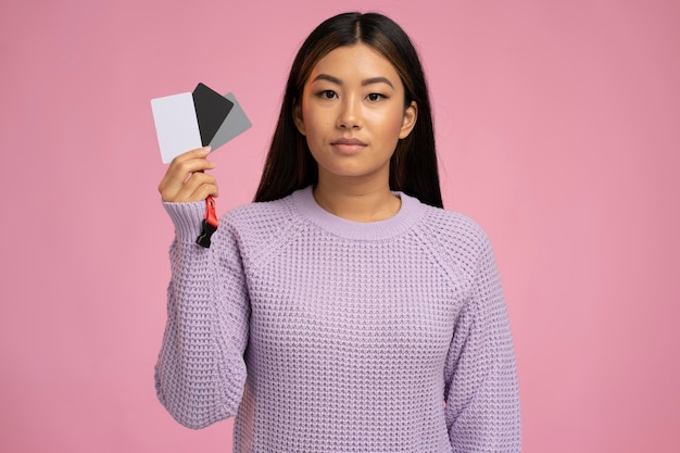 Image of positive dreaming pretty woman holding credit card and posing isolated over pink