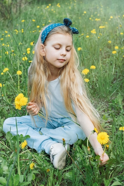 Image of pretty little girl sitting on dandelions field