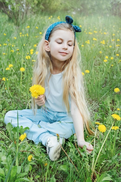 Image of pretty little girl sitting on dandelions field