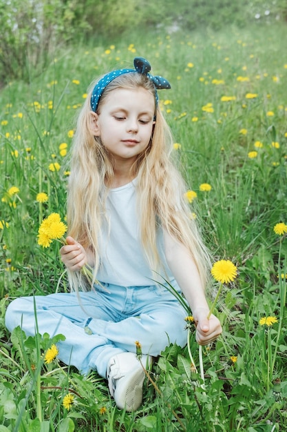 Image of pretty little girl sitting on dandelions field