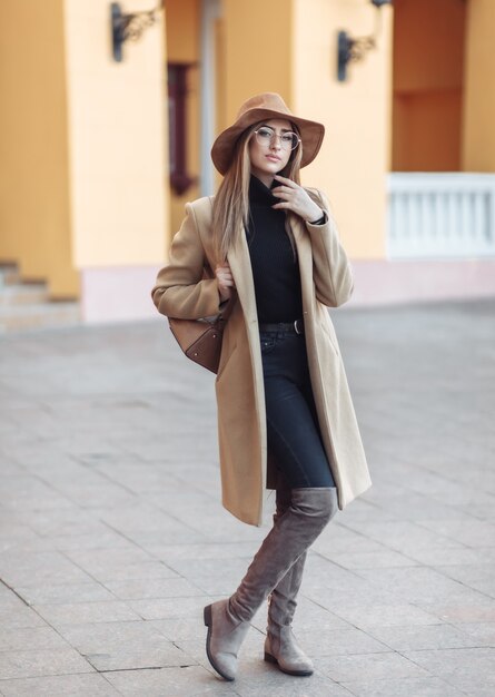 Image-shot of a young attractive woman wearing a coat and felt hat on a blurry background of city