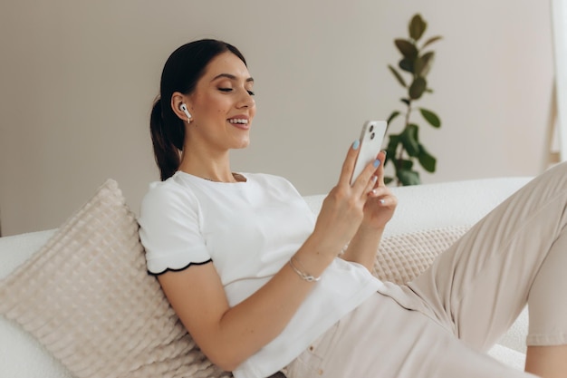 Image of a smiling woman using a mobile phone while sitting on a sofa