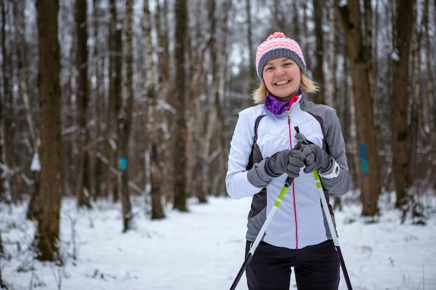 Image of smiling woman with skis in winter forest