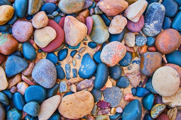 Image of Smooth multicolored stones against a sandy beach